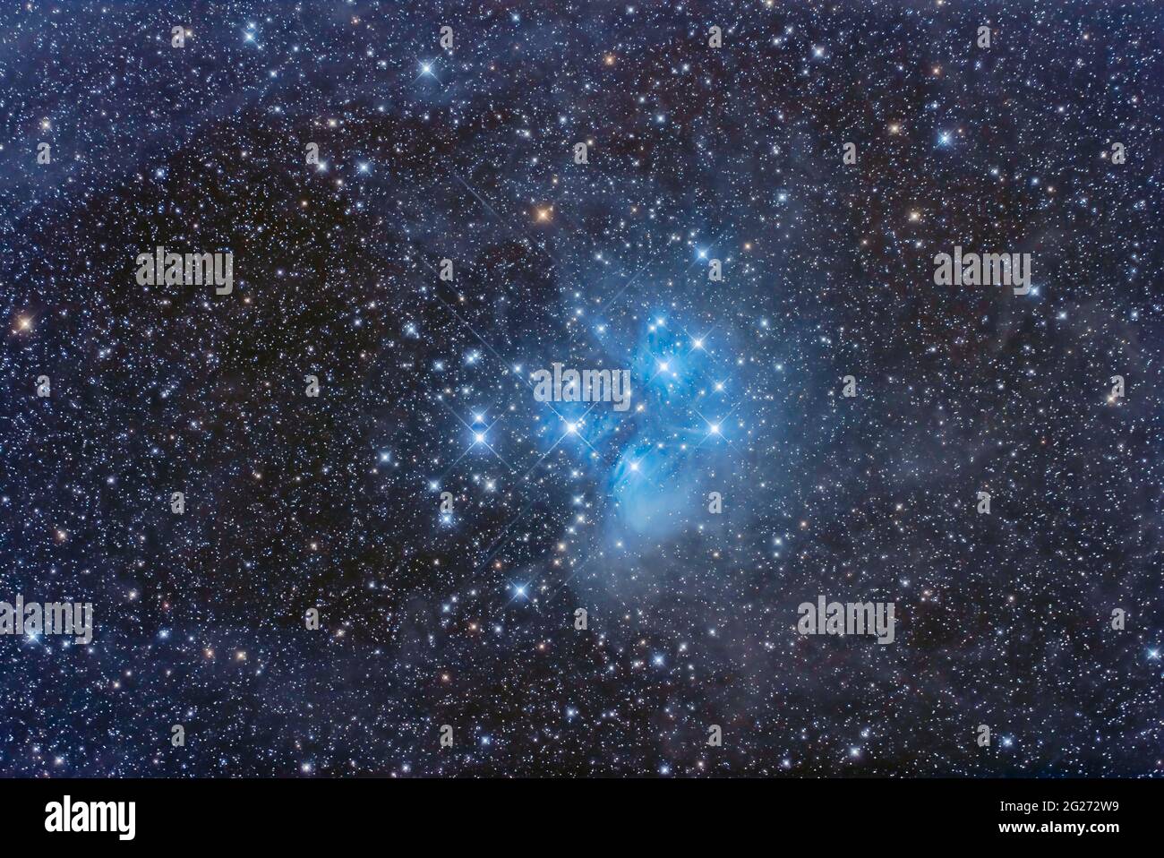 The Pleiades star cluster, Messier 45, amid the faint and dusty nebulosity that surrounds it. The stars of the Pleiades are passing through the dust c Stock Photo