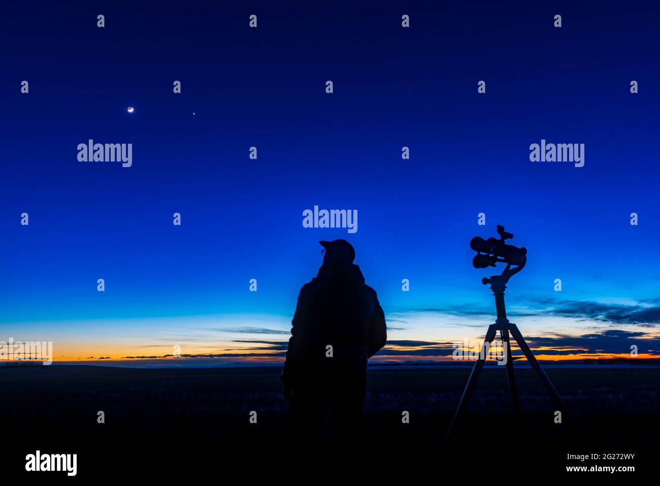 An astronomer looking at the waxing crescent moon near Venus. Stock Photo