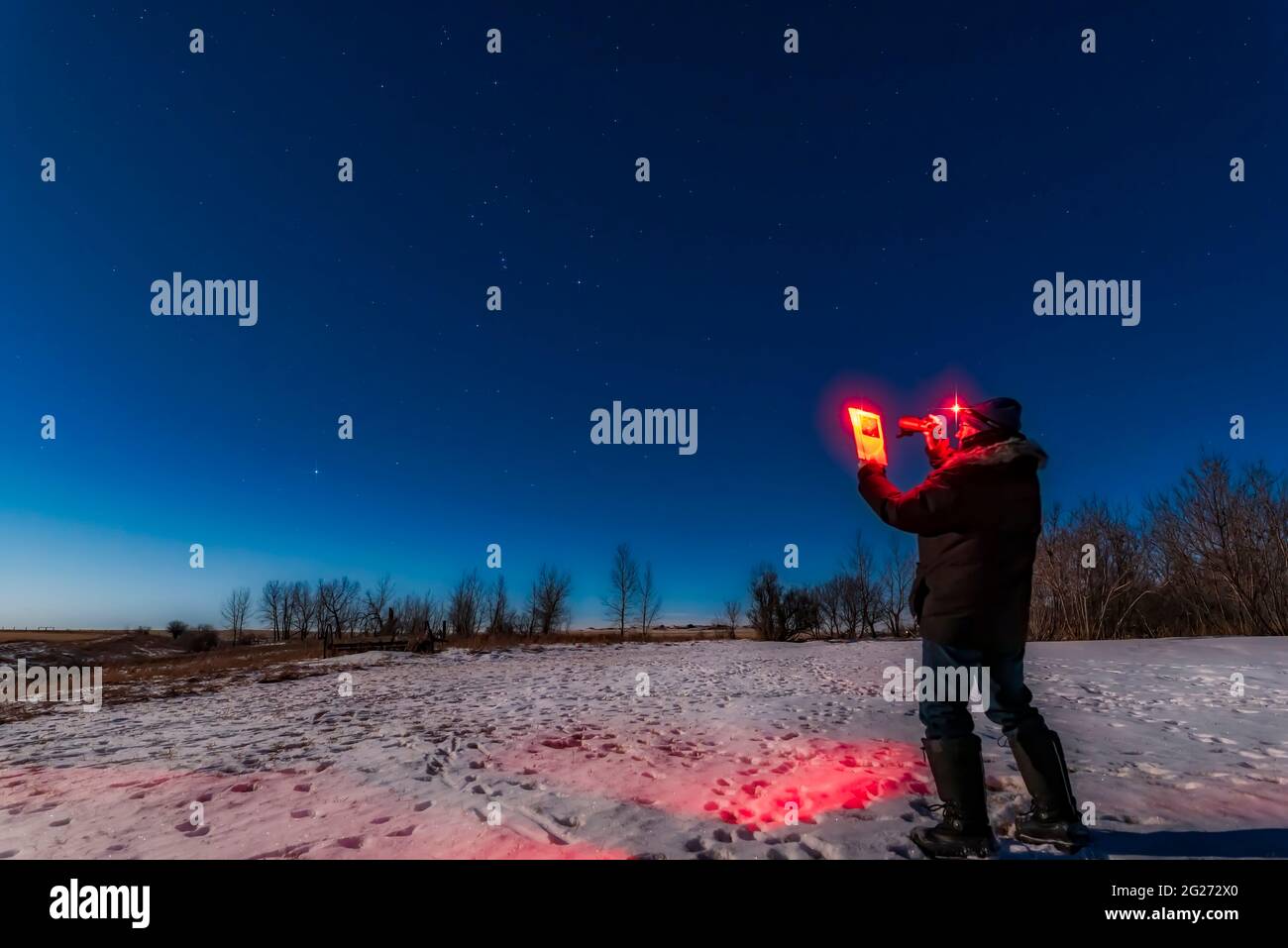 Astronomer using binoculars and guidebook to find targets in the night sky. Stock Photo