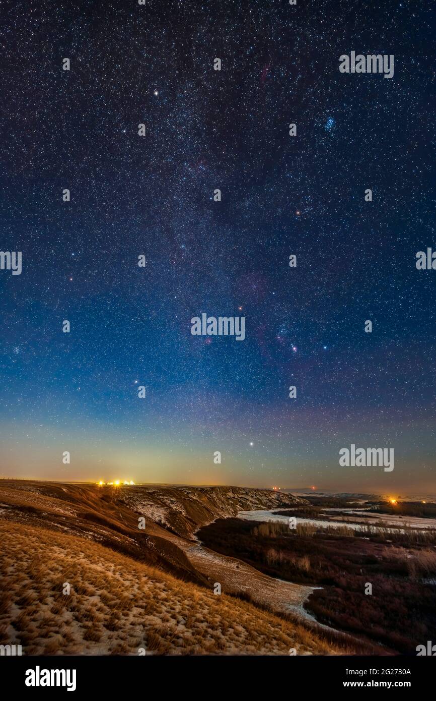 Orion and the winter stars and constellations rising above the Bow River in Alberta, Canada. Stock Photo