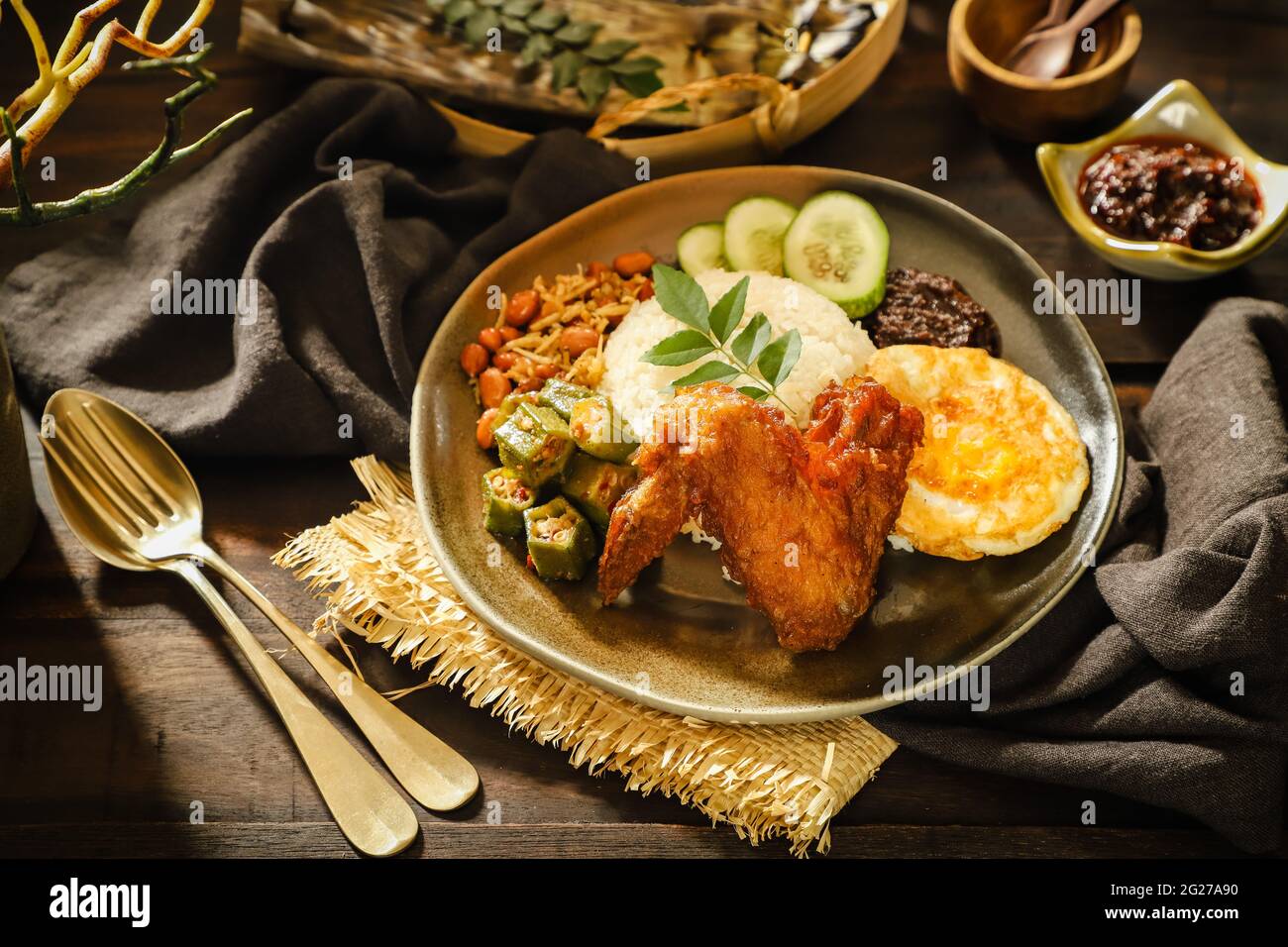 Nasi Lemak. Malay rice dish of fragrant rice with fried chicken, chili paste, peanuts, anchovies, egg. Stock Photo