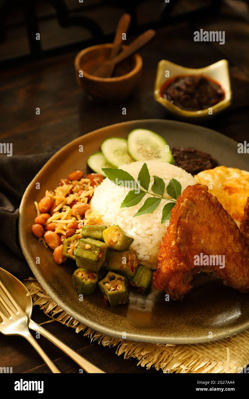 Nasi Lemak. Malay rice dish of fragrant rice with fried chicken, chili paste, peanuts, anchovies, egg. Stock Photo