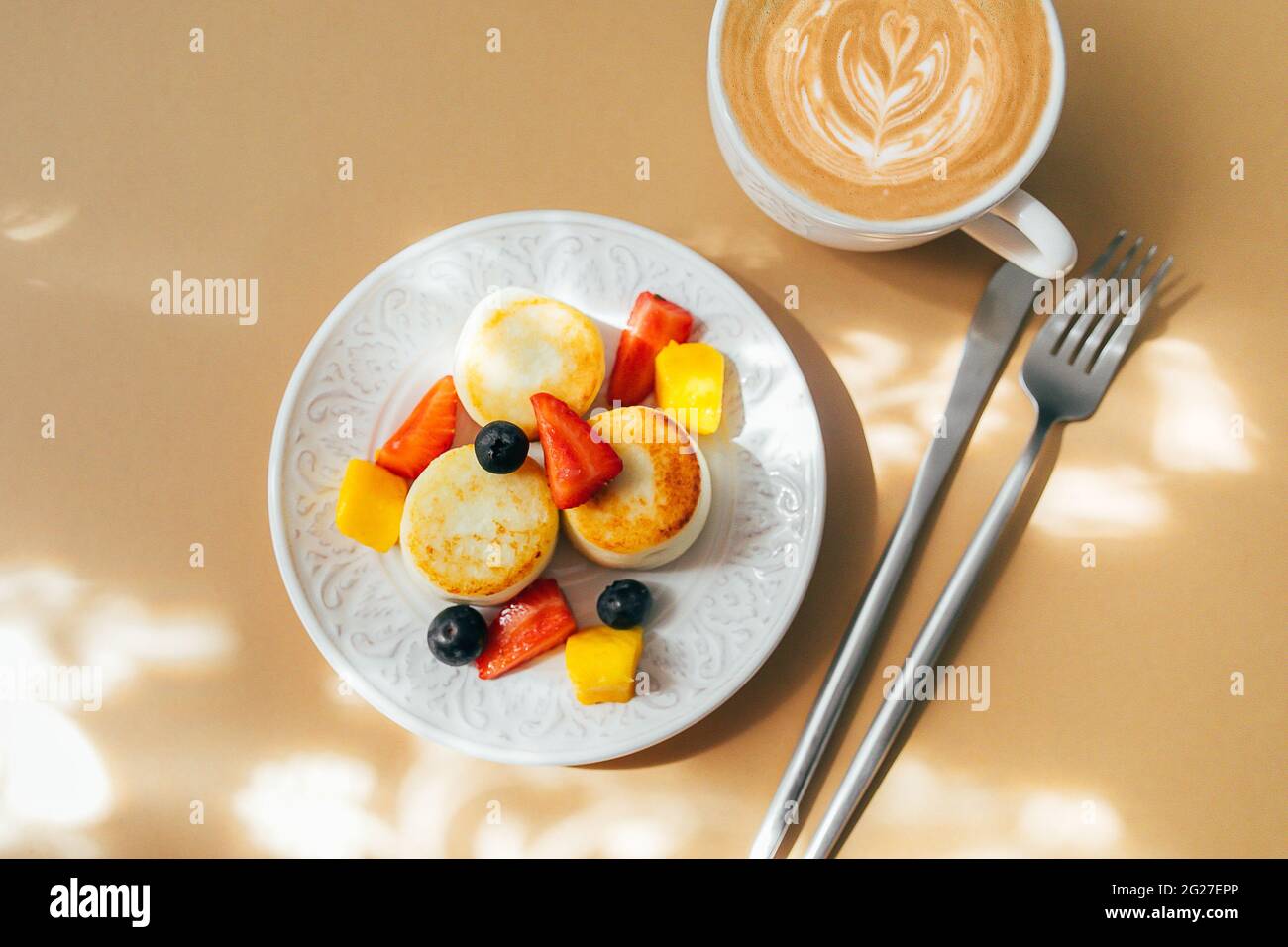 Cottage cheese pancakes on plate, cup of coffee. Syrniki with berry, top view. Stock Photo
