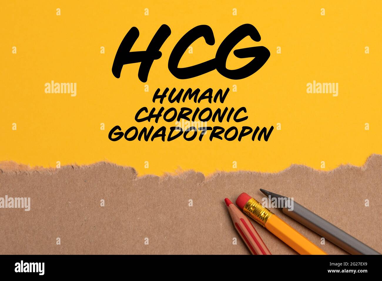 HCG human chorionic gonadotropin. Torn cardboard paper on yellow background. Stock Photo