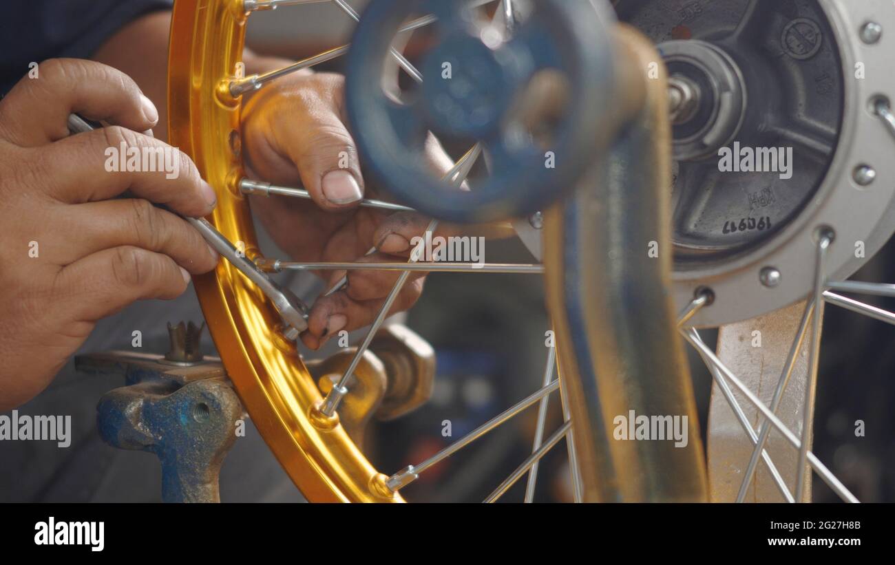 Technician man working motorcycle wheel has spokes weave up on mechanic