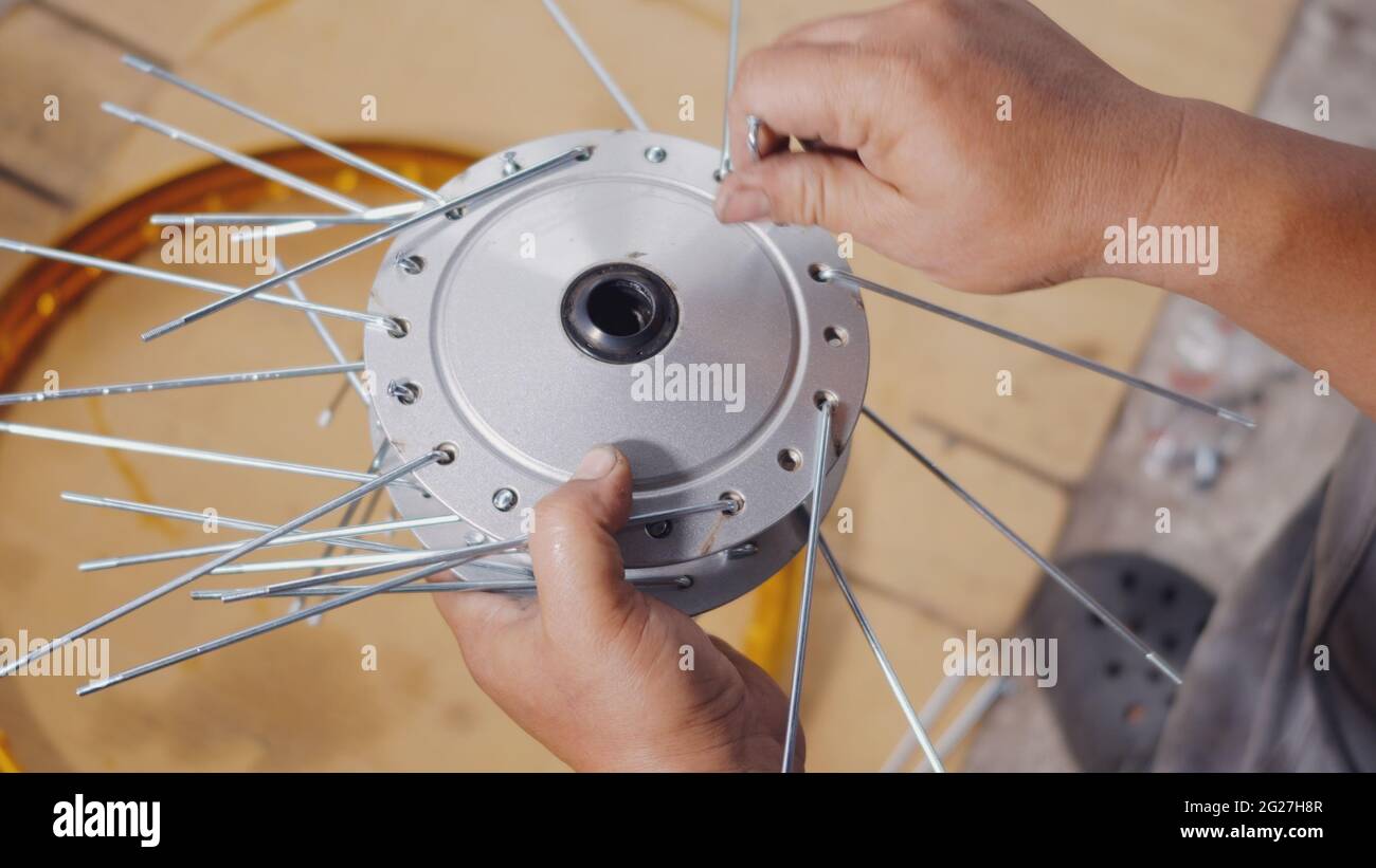 Technician man working motorcycle wheel has spokes weave up on mechanic