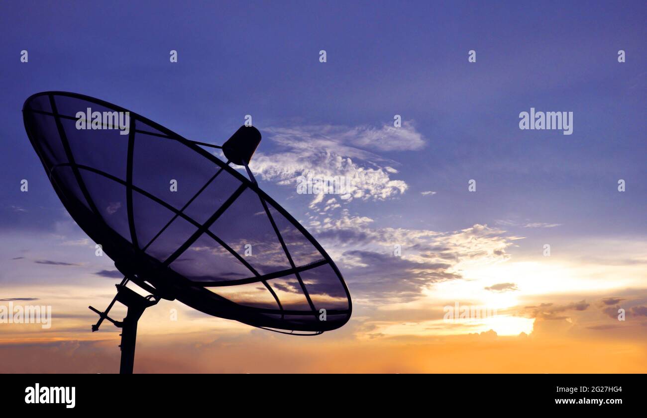 A black satellite dish on twilight sky background Stock Photo