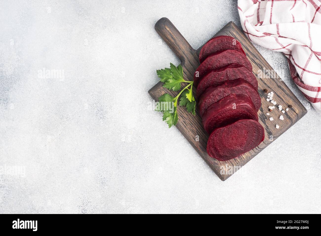 Slices of boiled beetroot on a cutting Board with parsley leaves on a wooden rustic background. Copy space, Stock Photo