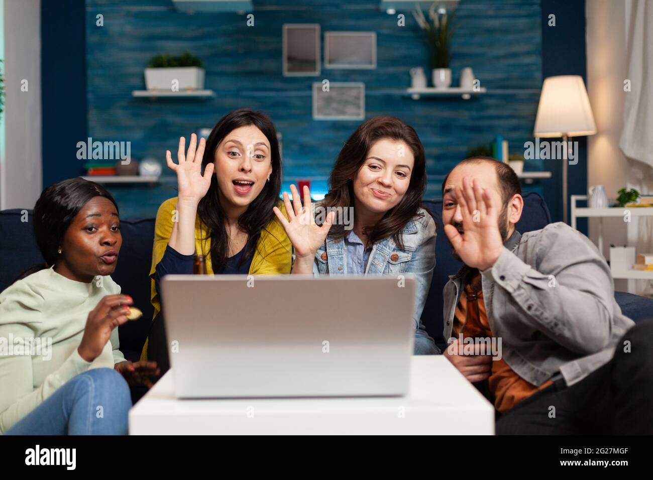 Happy multi-ethnic friends greeting her collegue during online videocall  meeting using laptop webcam. Group of multiracial people spending time  together on couch late at night during party Stock Photo - Alamy