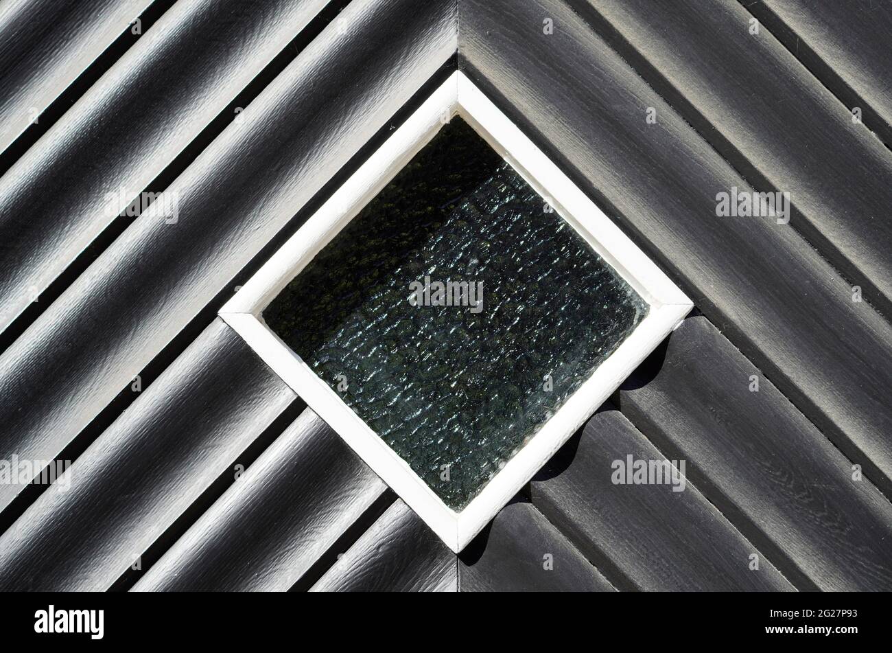 Old black wooden door with a glass insert. Peephole in the door. Symmetrical diamond shape Stock