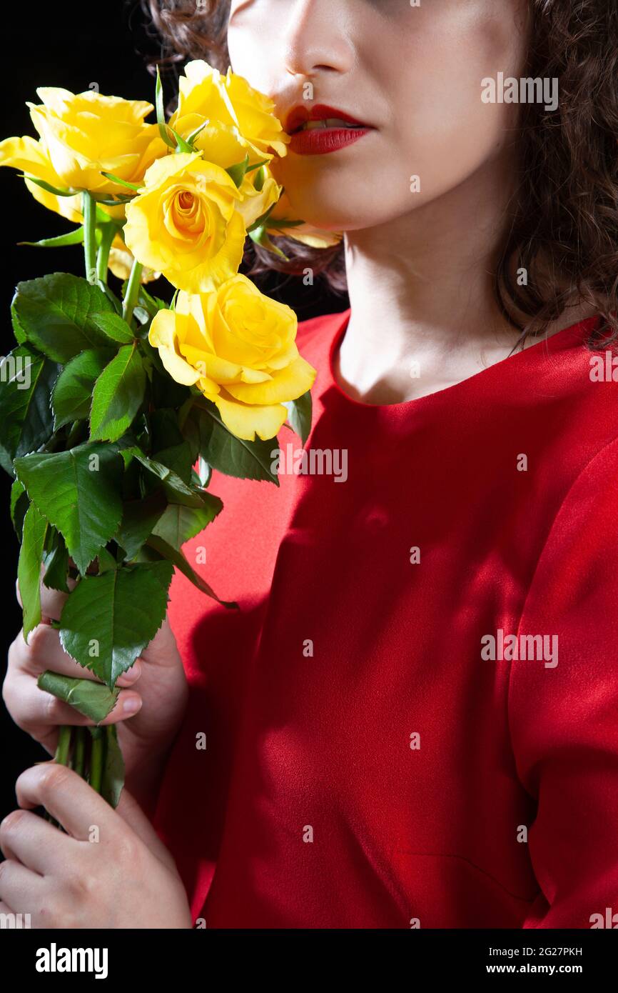 Brunette in Red Dress Holding Yellow Roses Stock Photo