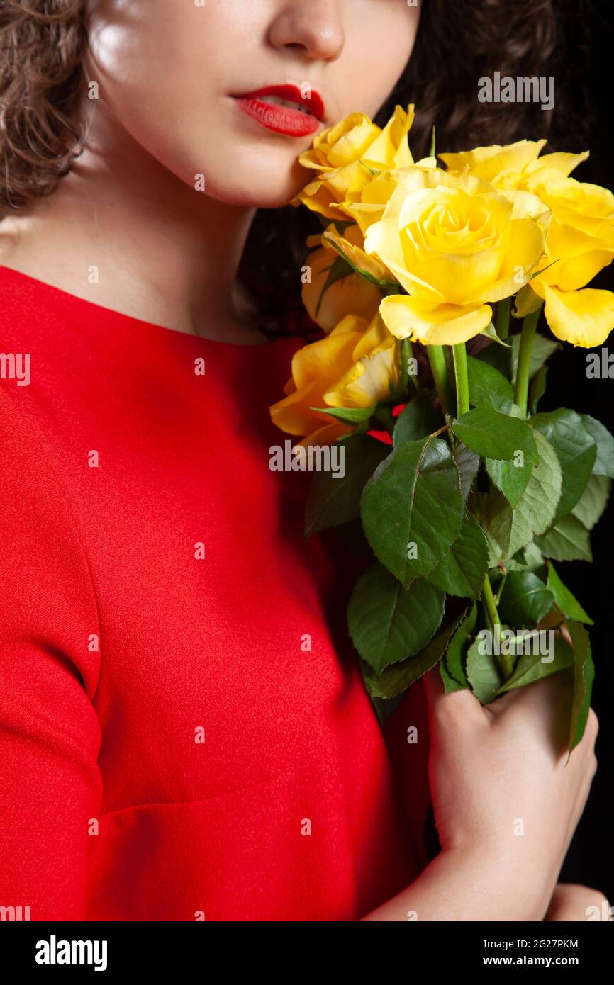 Brunette in Red Dress Holding Yellow Roses Stock Photo