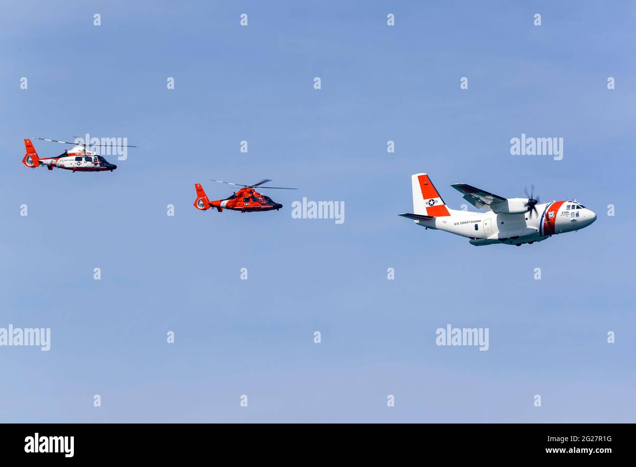 A U.S. Coast Guard C-27J flying in formation with two MH-65 Dolphin helicopters. Stock Photo