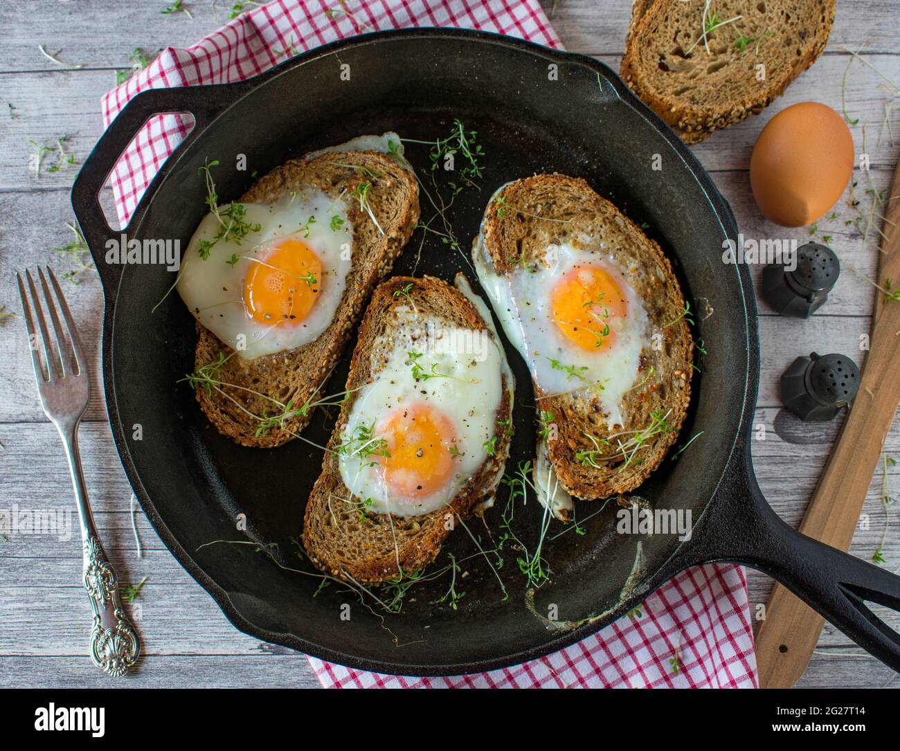 Egg in a whole served in cast iron pan on rustic and wooden table