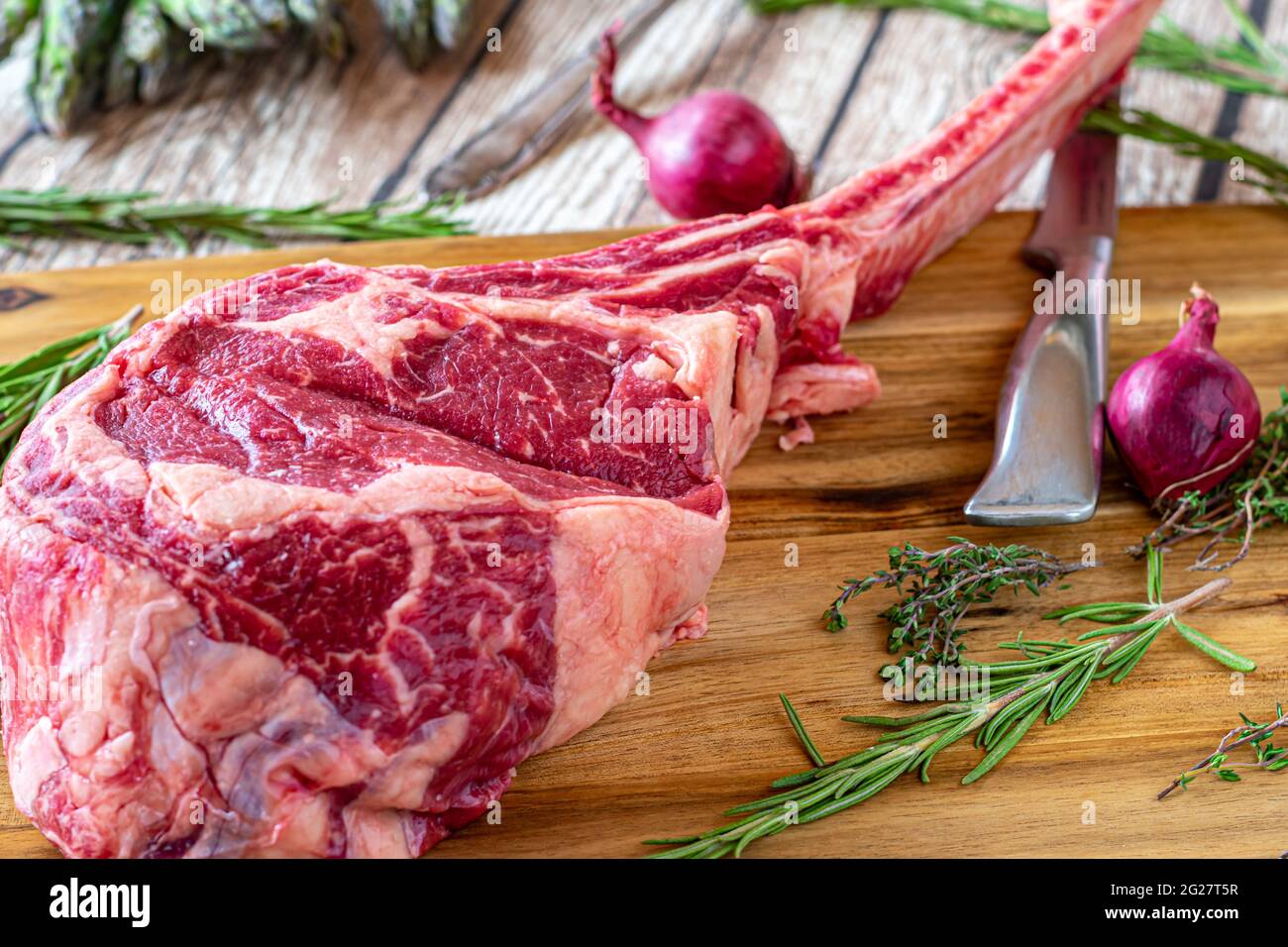 Irish tomahawk  rib eye steak on rustic wooden table background with knife and herbs Stock Photo