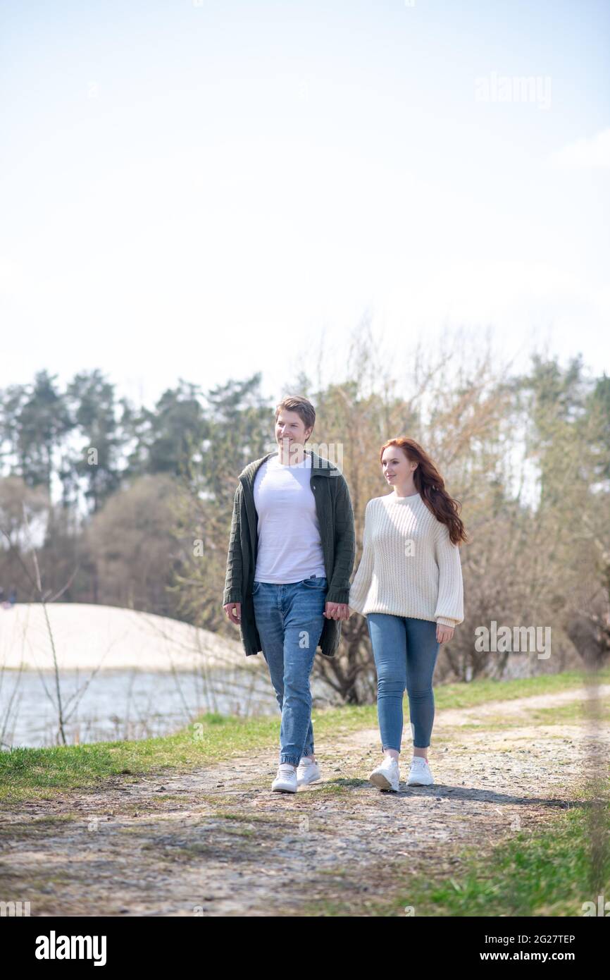 Happy woman and man holding hand walking outdoors Stock Photo
