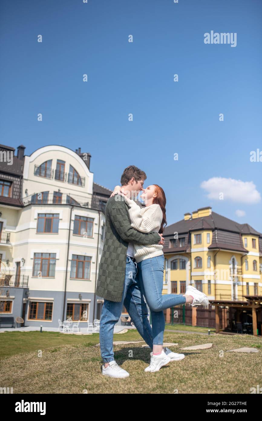 Man and woman hugging outdoors against background of houses Stock Photo