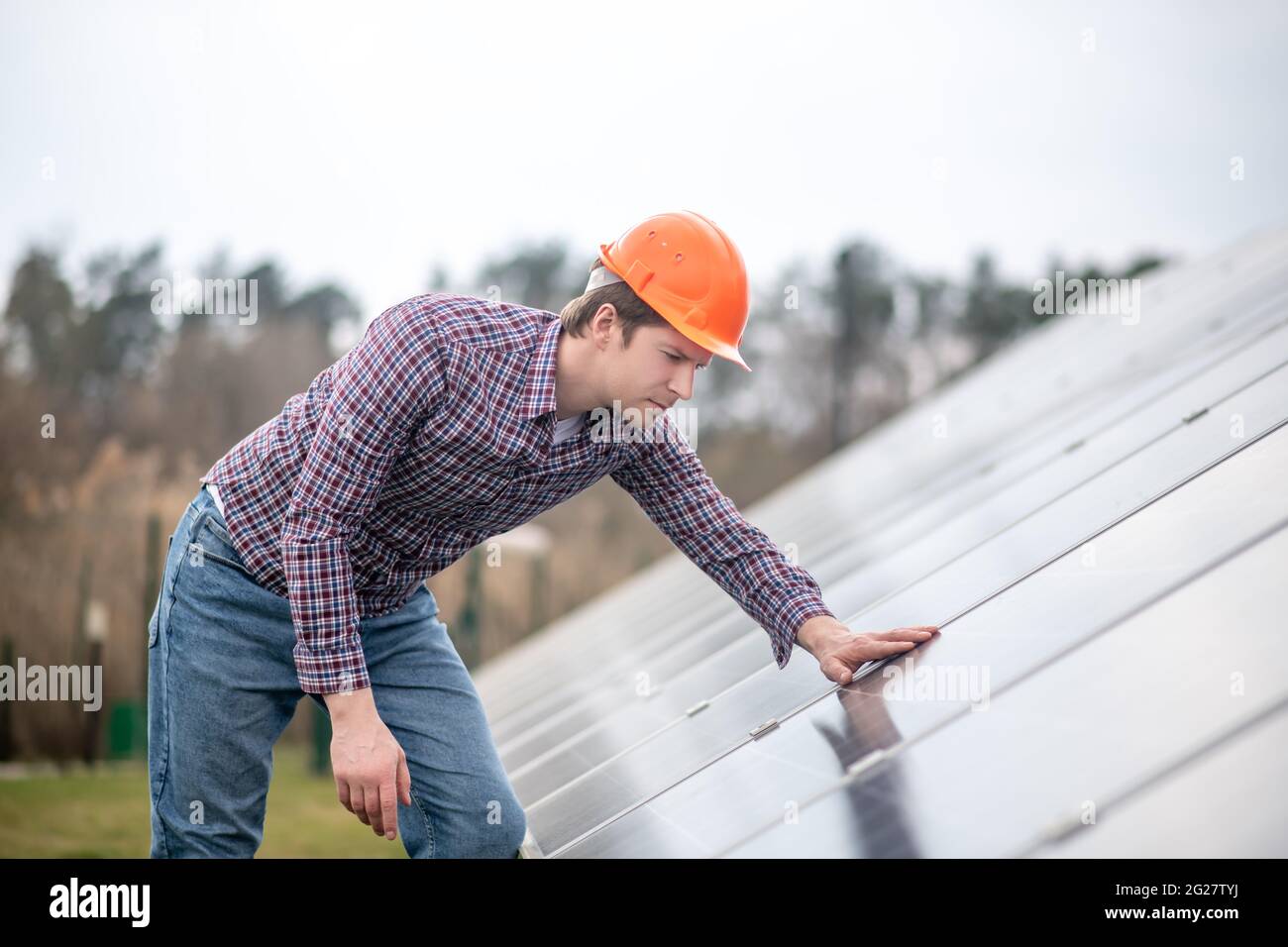 Man in helmet looking at surface of building structure Stock Photo