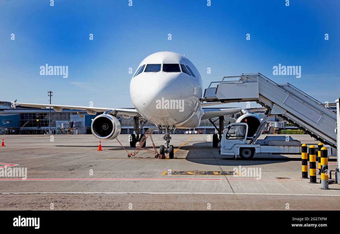 Boarding passengers on the plane. Boarding bridge. Aircraft on the apron. The plane lands at the empty international airport. Loading luggage. White airplane. Terminal Runway. Copy space. Stock Photo