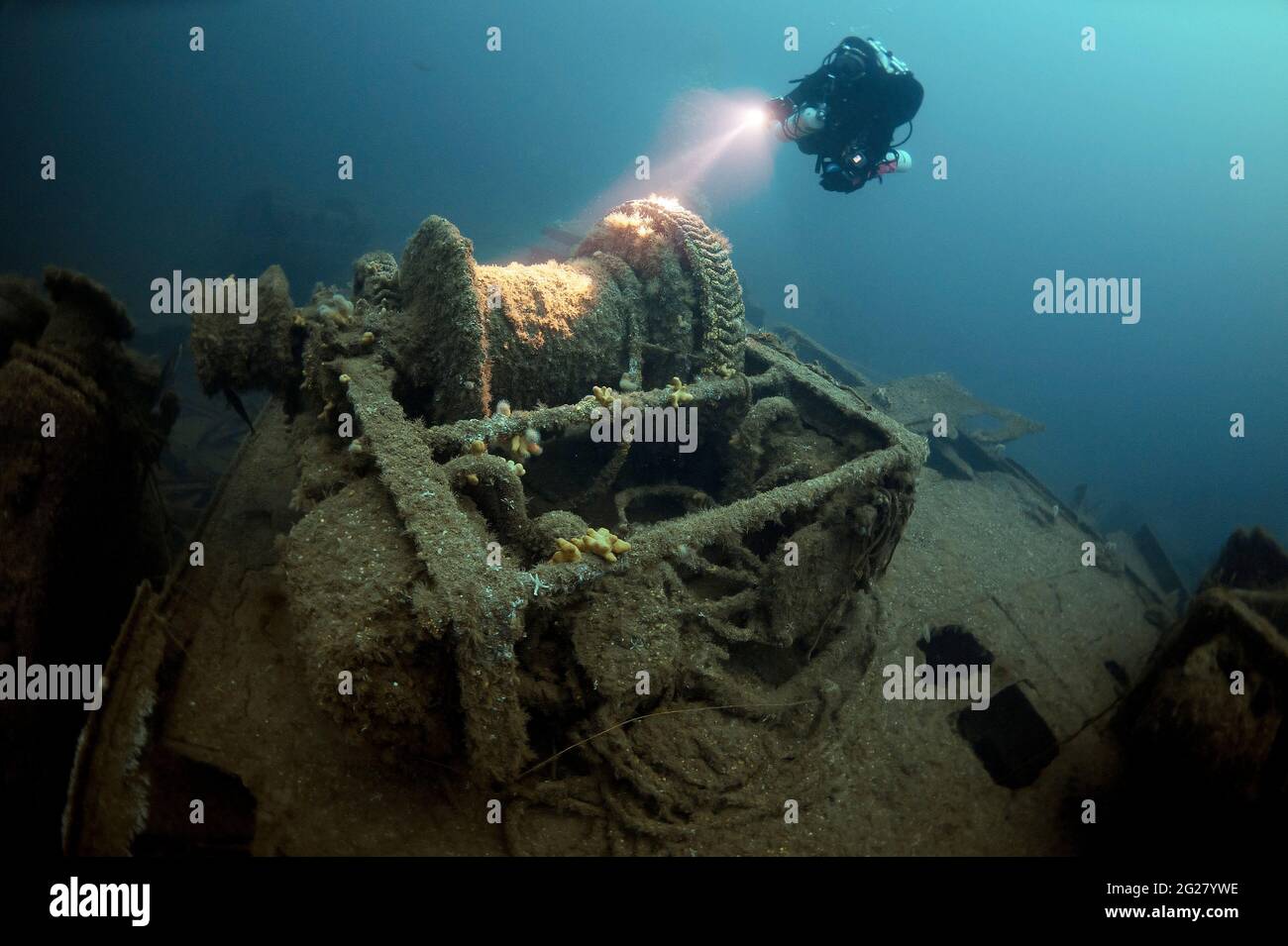 Diver exploring the SS Empire Heritage shipwreck, shown above the winch. Stock Photo