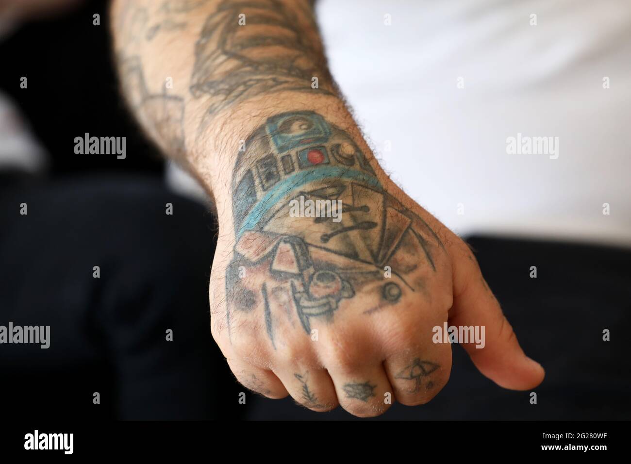 Tattoos of an English rose, Mr Bean, Del Boy and R2-D2 pictured on a mans arm in Portsmouth, Hampshire, UK. Stock Photo