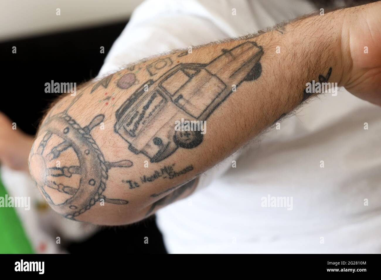 Tattoos of an English rose, Mr Bean, Del Boy and R2-D2 pictured on a mans arm in Portsmouth, Hampshire, UK. Stock Photo