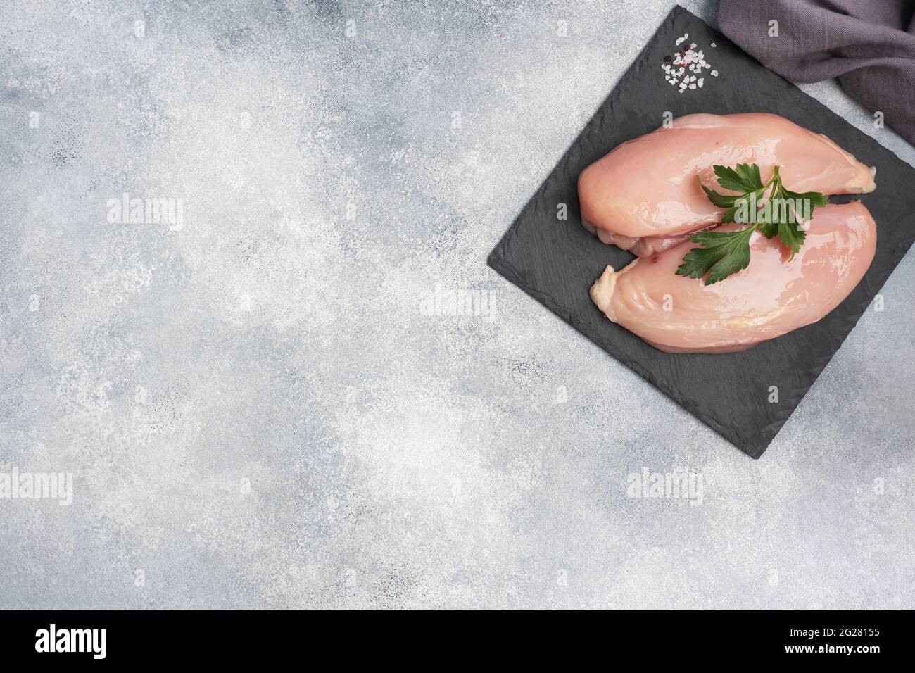 Raw chicken breast fillet, raw chicken meat on a black stand, gray background Stock Photo