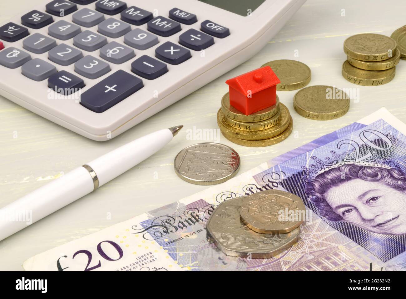 A still life with pound notes, coins and a toy house. A metaphor on property finance. Stock Photo