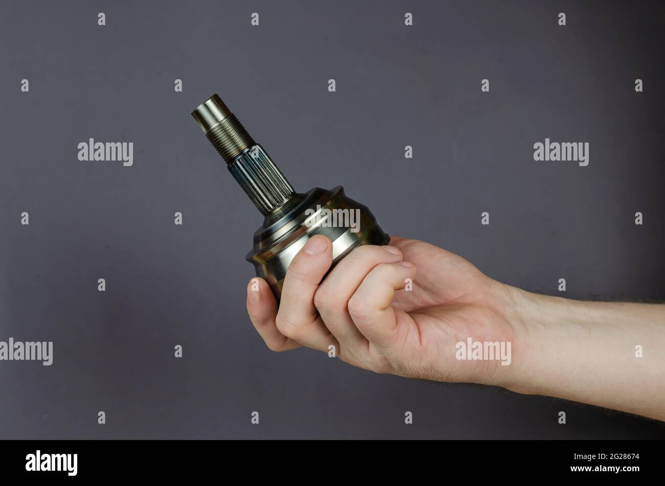 A man demonstrates a Drive shaft joint against a gray background. New