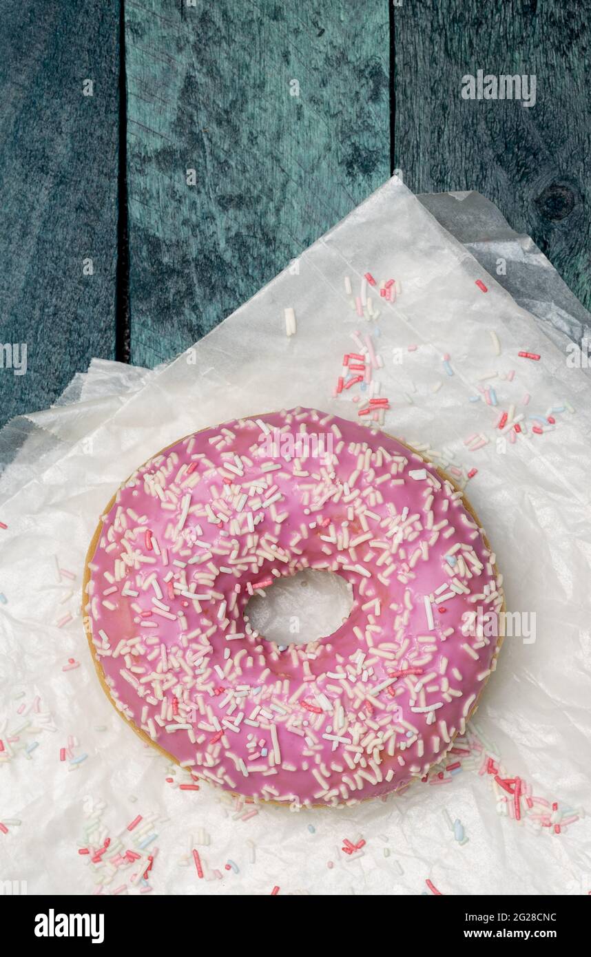 Donut with sugar sprinkles on a turquoise wooden background. Stock Photo