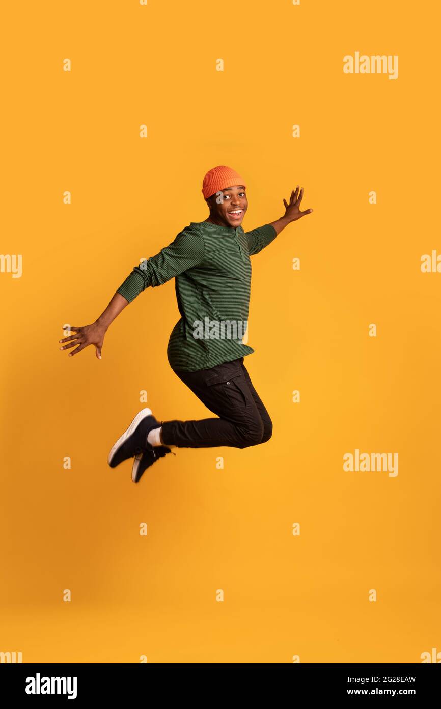 Portrait Of Cheerful Black Young Guy Jumping In Air Over Yellow