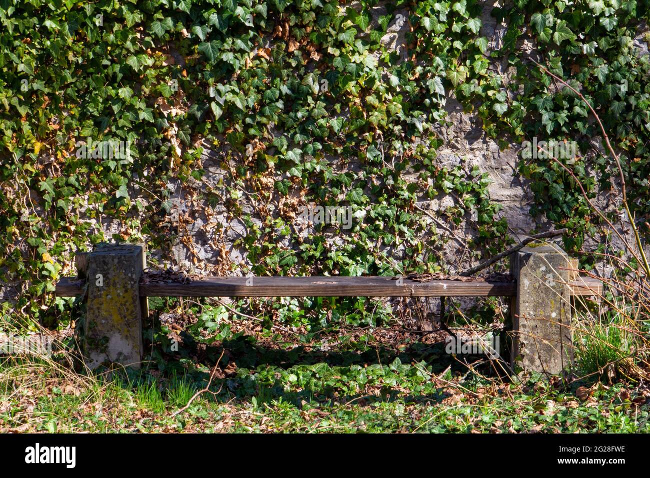 Old damaged and weathered bench in front of a natural stone wall ...
