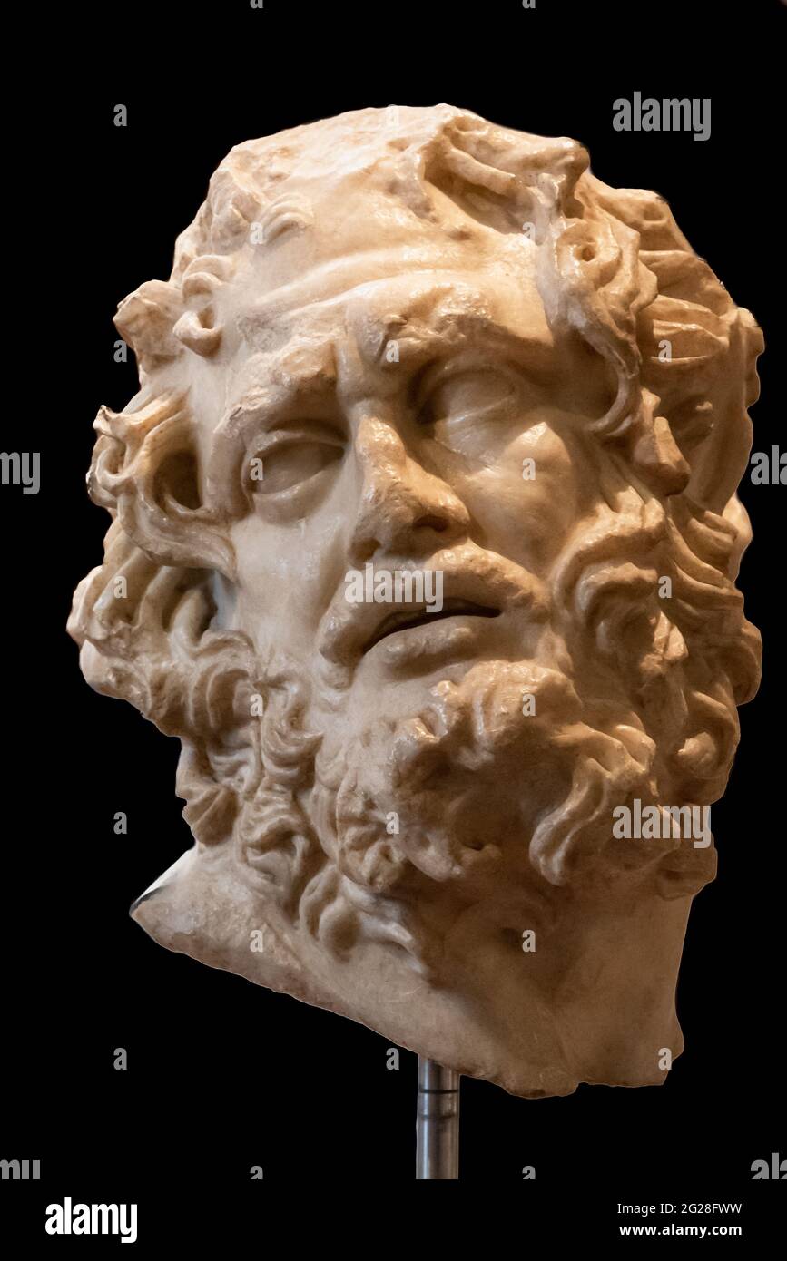 Close-up on head of ancient marble statue representing a hairy sad man Stock Photo