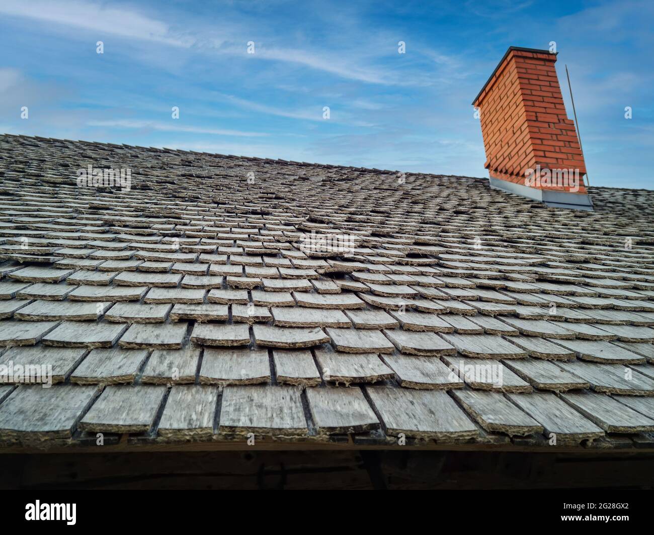 wood roofing - roof with old wooden shingles against blue sky Stock Photo
