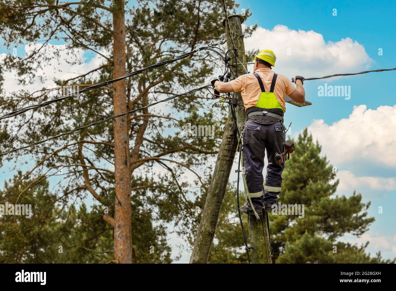 electrical lineman connecting wires high on electric pole. powerline maintenance and repair Stock Photo