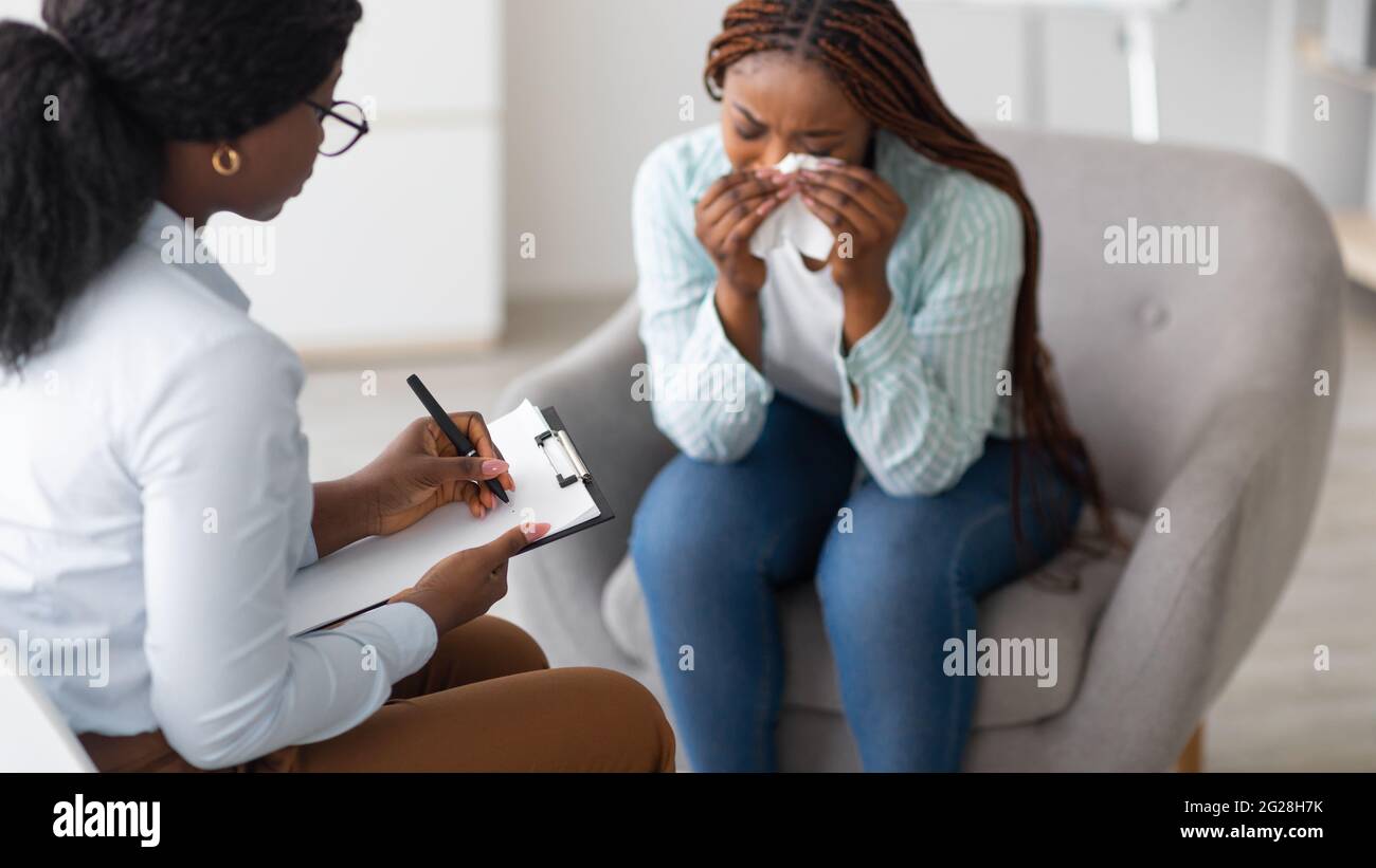 Unhappy black young woman crying at psychologist's office, panorama Stock Photo