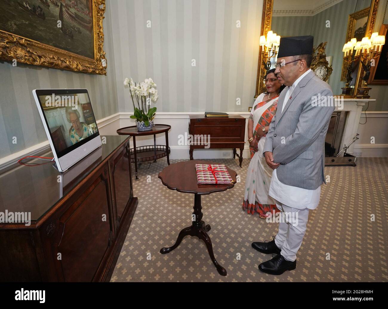 Queen Elizabeth II appears on a screen via videolink from Windsor Castle, where she is in residence, during a virtual audience to receive His Excellency Lokdarshan Regmi, the Ambassador of Nepal, and his wife Chandra Kala Regmi, at Buckingham Palace, London. Picture date: Wednesday June 9, 2021. Stock Photo
