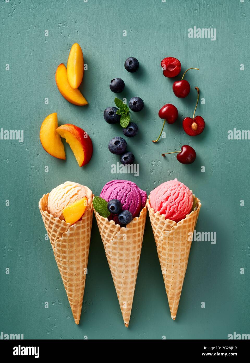 Assorted of ice cream in cones on blue background. Colorful set of ice cream of different flavours. Ice cream isolated with nuts, fruits and berries. Stock Photo