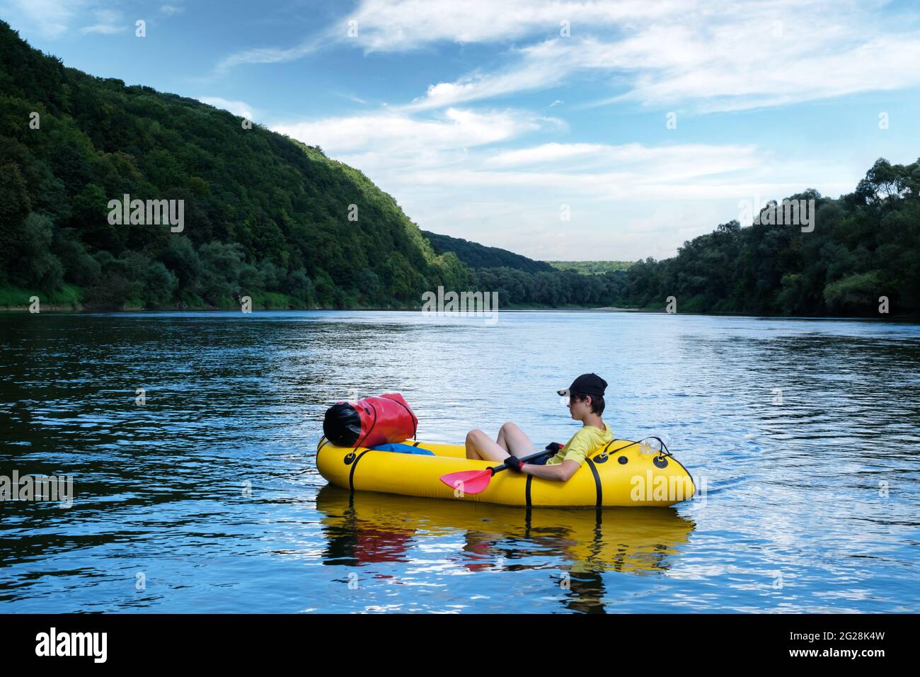 Tourist on yellow packraft rubber boat with red padle on a sunrise river. Packrafting. Active lifestile concept Stock Photo