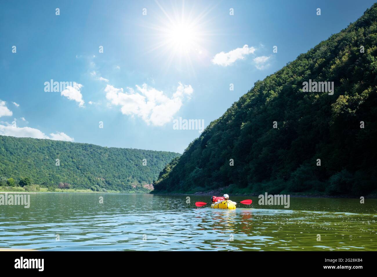 Tourist on yellow packraft rubber boat with red padle on a sunrise river. Packrafting. Active lifestile concept Stock Photo