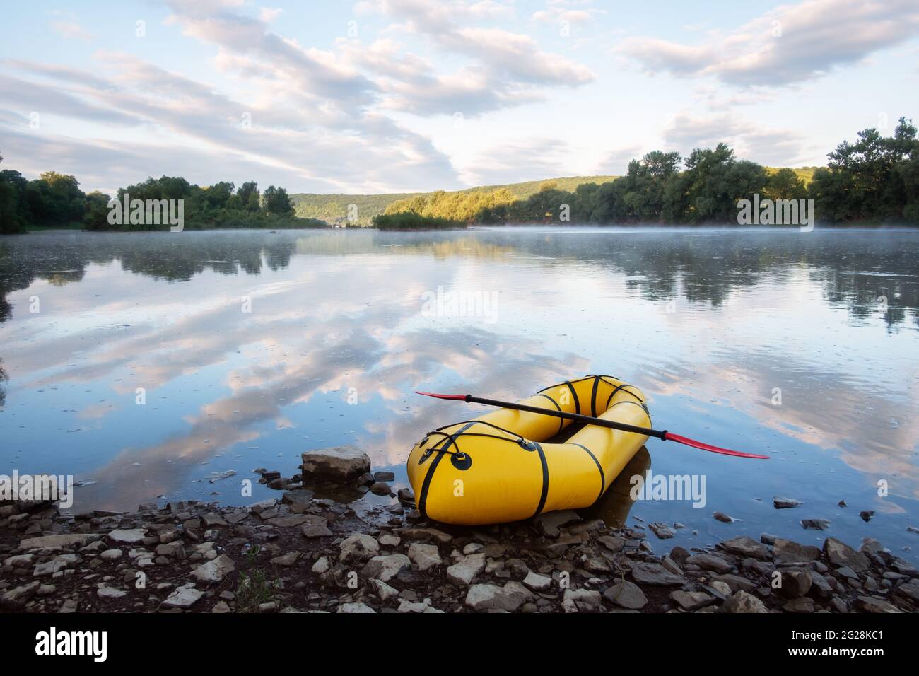 Yellow packraft rubber boat with red padle on a sunrise river. Packrafting. Active lifestile concept Stock Photo