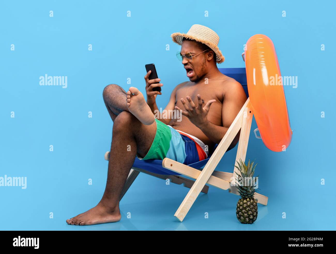 Frustrated black guy shouting at smartphone, feeling stressed, having bad internet connection on summer vacation Stock Photo
