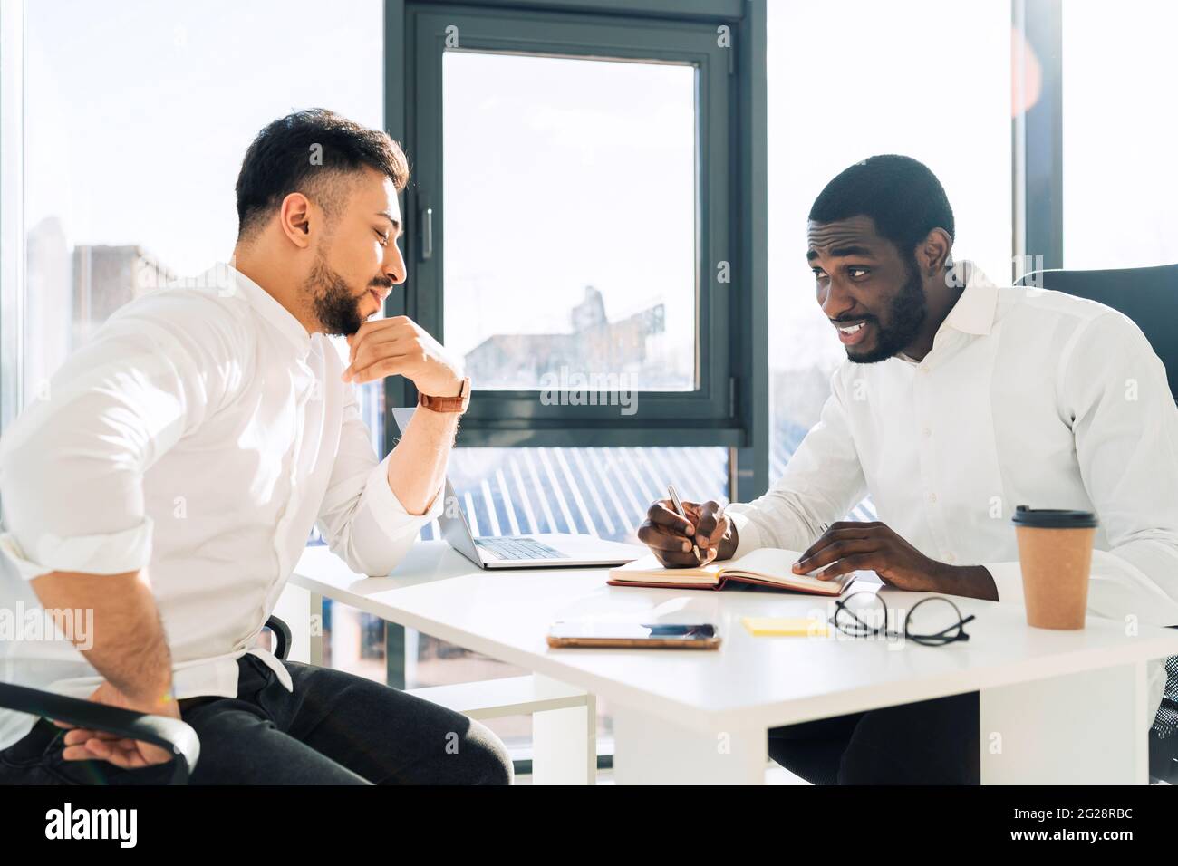 Two mulracial office workers hold meeting in the office Stock Photo