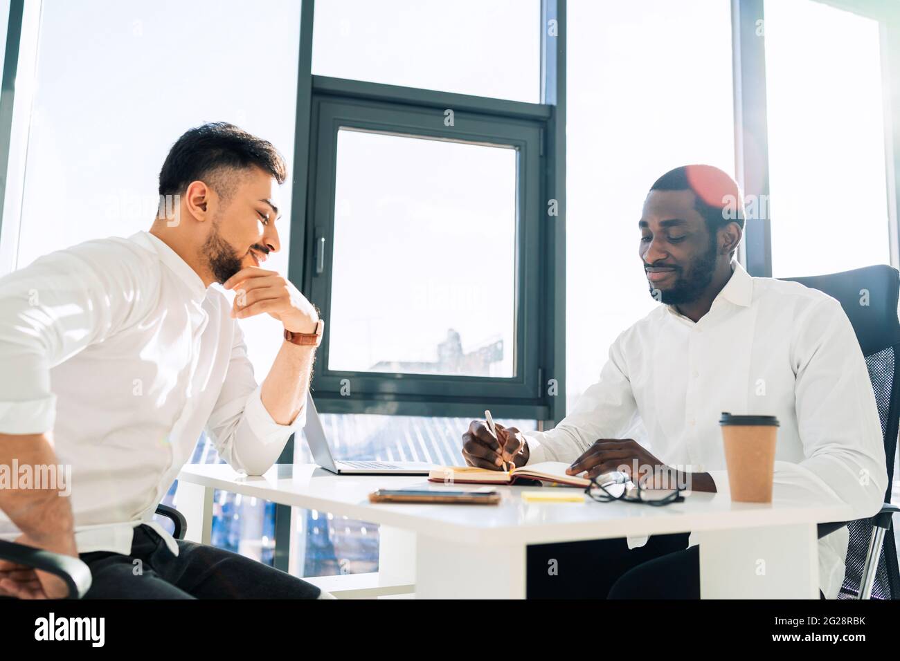 Two mulracial office workers hold meeting in the office Stock Photo