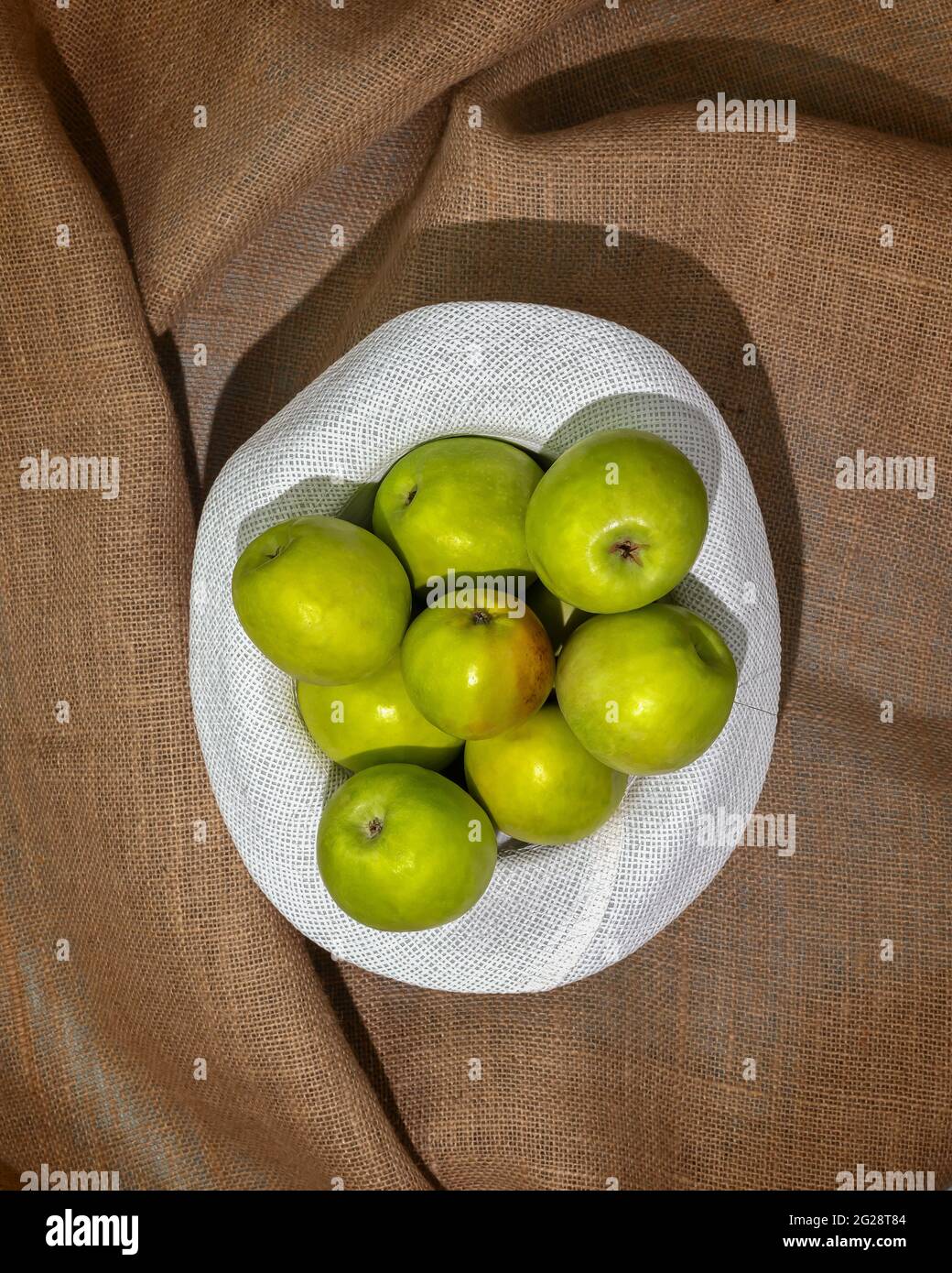 Concept of a local market, farm fruits and Harvest Day celebration, apple picking. Ripe, green apples in a summer white hat on a textile background Stock Photo
