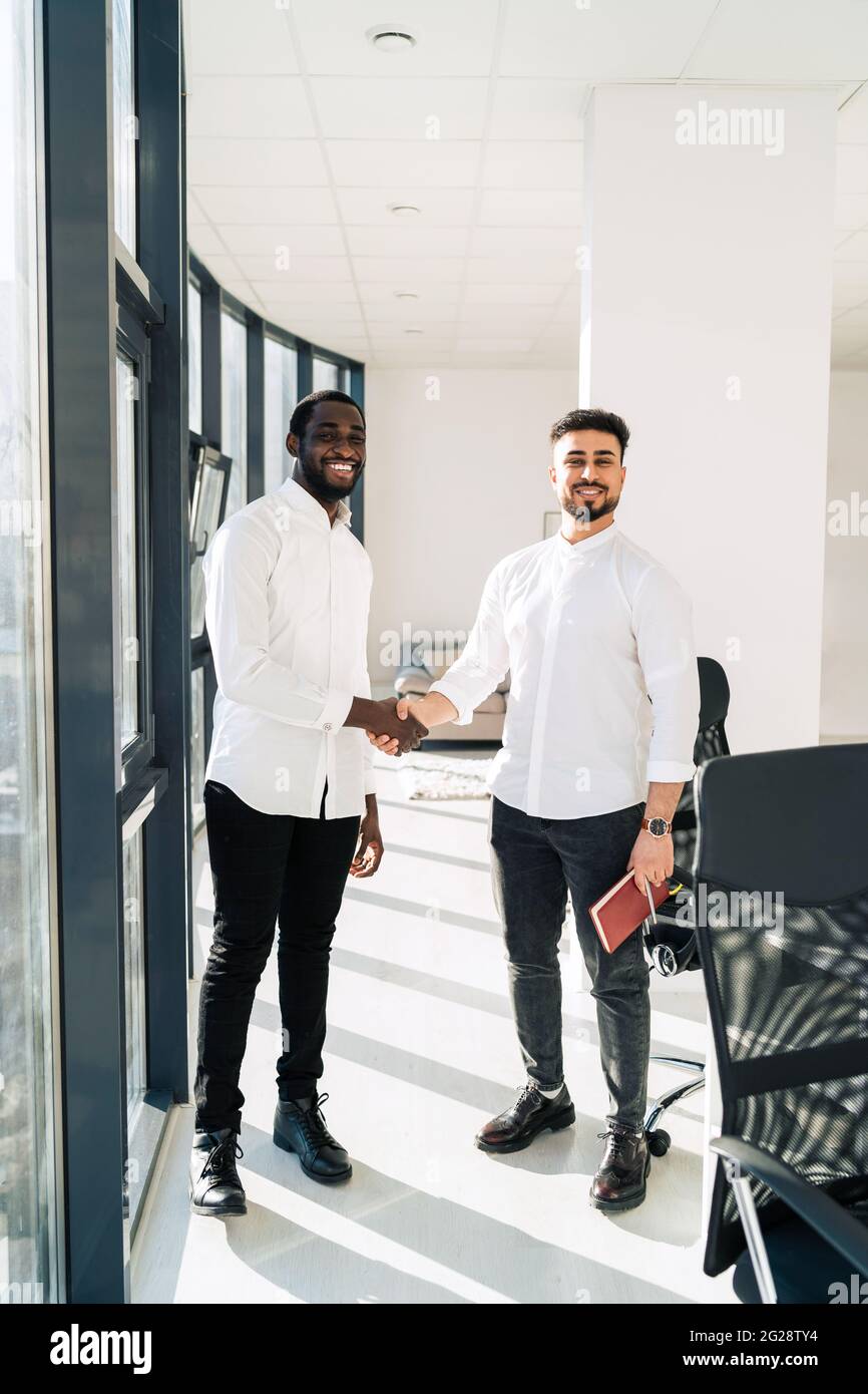 Two multiracial businessmen shake hands in office Stock Photo