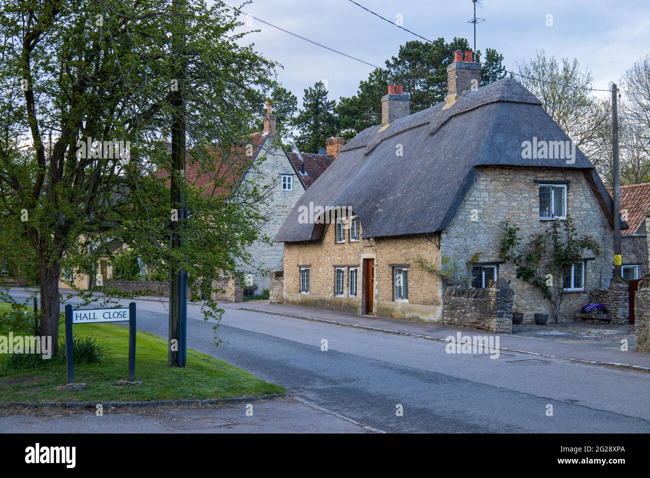 Pretty cottage with thatched roof at corner of Hall Close and High Street, Sharnbrook, Bedfordshire, England, UK Stock Photo