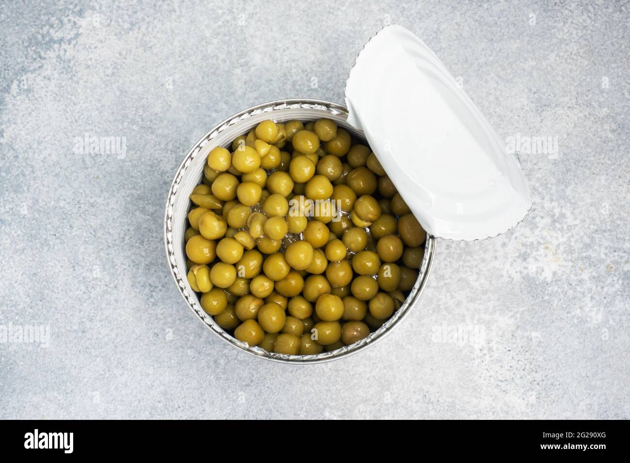 Tin open jar with canned peas on a gray concrete background. copy space Stock Photo