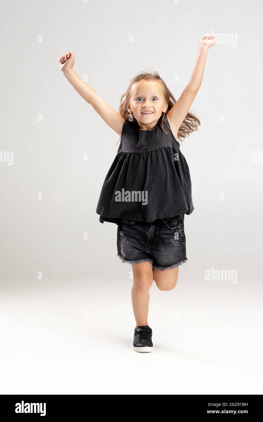 Smiling cute girl running over white studio background. Caucasian model with long flowing hair in summer dress. Stock Photo
