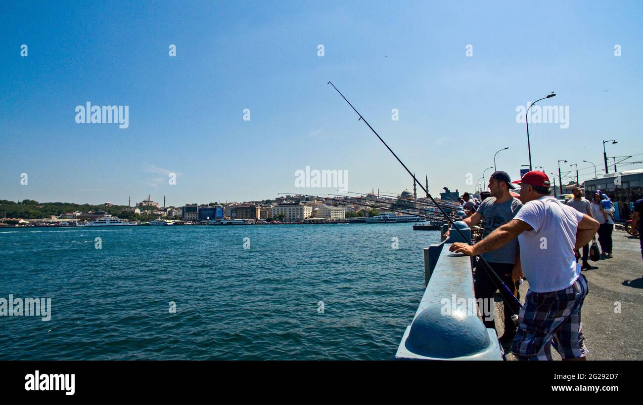Fishermen on the Galata Bridge in Karakoy. Istanbul, Turkey. 06-22-2019. People with fishing rod fishing from the bridge. Hagia Sophia mosque Stock Photo